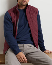 man wearing burgundy wine colored quilted vest over a navy sweater