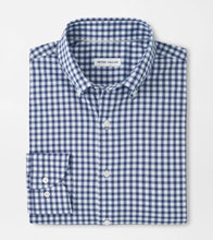 Folded blue and white checkered shirt with 'Peter Millar' label on a light gray background