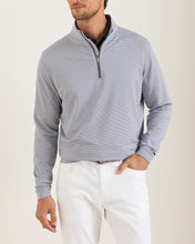 man wearing grey quarter-zip and white pants