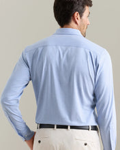 Man wearing a light blue dress shirt and beige pants against a plain background