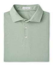 Folded light green polo shirt with 'Peter Millar' label on a white background