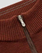 Close-up detail of a ribbed knit half-zip sweater in a warm rust brown color, showing the silver metal zipper pull and a dark brown inner zipper track.