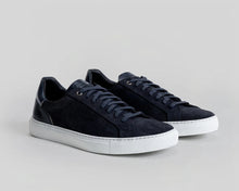 Navy blue sneakers with white soles on a light gray background