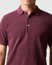 man in burgundy polo and navy shorts