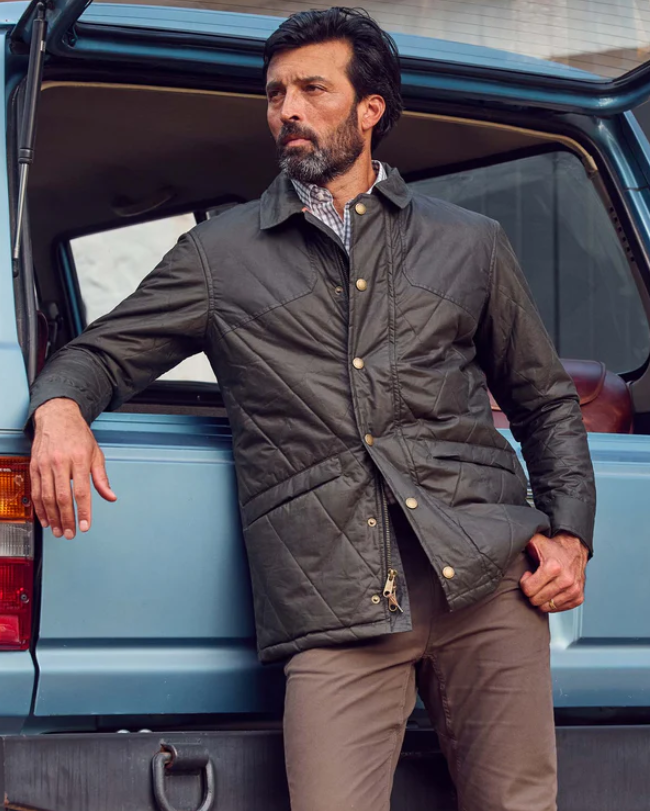 Man standing next to a blue van wearing a dark jacket.