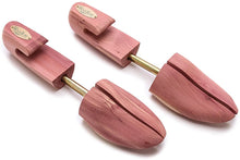 A pair of brown cedar wood shoe trees with brass-plated steel hardware.