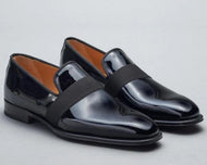 Pair of black patent leather shoes on a light gray background