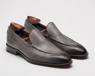 A pair of smoke grey, hand-burnished, pebble grain leather loafers with a leather sole, displayed against a white background.
